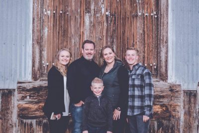 John Morris and the Morris family, owners of Canyon Creek Electric, photographed against a weathered wood backdrop in Montrose, Colorado